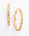 A chic accent to any outfit, these substantial 2-inch hoops are crafted in rich 14K yellow gold with an intricately engraved design. For pierced ears only.