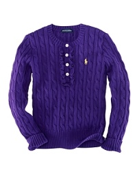 A traditional cable-knit sweater takes a feminine turn with delicate ruffle trim along the buttoned front. A traditional cable-knit sweater takes a feminine turn with delicate ruffle trim along the buttoned front.