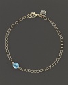 A single faceted blue topaz adds a spot of brilliant color to elegant 18K yellow gold links. By Carelle.