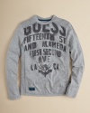 GUESS cotton crewneck pullover adds edge with allover stencil logo print.