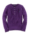 A traditional cable-knit sweater takes a feminine turn with delicate ruffle trim along the buttoned front.