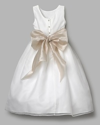 Charming party dress in sleek organza. Empire waist with coordinating sash and full, pleated skirt. Crew neckline, wide shoulder straps and four faux pearl button closures at the back. Charming party dress in sleek organza. Empire waist with coordinating sash and full, pleated skirt. Crew neckline, wide shoulder straps and four faux pearl button closures at the back.