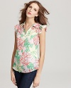 Usher in the warm weather in a cheerful Lilly Pulitzer shirt, flourished in a bright floral print with daintily ruffled cap sleeves.