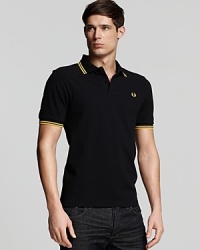 Widely known as the pioneer of Mod, British street fashion, Fred Perry polos have become an iconic fashion silhouette. A sporty polo with contrast double stripe trim and embroidered logo at left chest. Slim fit.