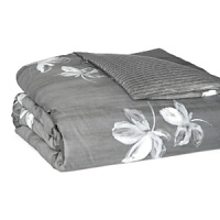Large floral blossoms in watercolor shades of white and grey dance across a dark grey background on duvets and shams in this collection by Vera Wang. Reverse is a suiting pinstripe.