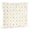 A detailed, textural decorative pillow covered in folded fabric flowers and anchored by multicolored embroidered dots.