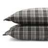 Inspired by the refined polish of menswear, this relaxed collection pairs solid brushed cotton and twill with faux suede trim and plaid. Sheets and pillowcases are in a soft cotton bold plaid in a grey and white palette.