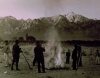 1943 Burning leaves, autumn dawn, Manzanar Relocation Center, California / photograph by Ansel Adams. SUMMARY: Group of men and boys standing around a small brush fire holding shovels, a pitchfork stands in the right foreground, mountains in background. V