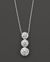 White gold bezel-set diamond necklace in three-stone drop design. With signature ruby accent. Designed by Roberto Coin.