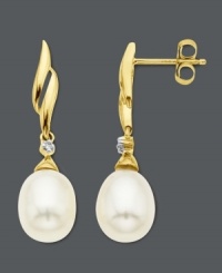 Incorporate traditional elegance into your look. Drop earrings feature a unique swirl setting crafted in 14k gold with cultured freshwater pearl drops (7 mm x 9 mm) and a sparkling diamond accent. Approximate drop: 1 inch.