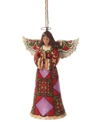 A distinct quilt pattern in red, plum and green make this praying angel ornament more striking than serene, and undeniably beautiful. With the unique folk-art style of Jim Shore. A distinct quilt pattern in red, plum and green make this praying angel ornament more striking than serene, and undeniably beautiful. With the unique folk-art style of Jim Shore.