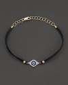 Diamonds and blue sapphires in 14K. yellow gold from a dazzling evil eye charm, strung on a leather rope. By Meira T.