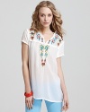Floral embroidery pops on this white Johnny Was top, adorned with playful ruffles for an island-inspired look. Keep things punchy and pair it with color denim or tone the style down and partner with LBPs.