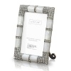 A unique metal frame with precious mother of pearl features a fully studded four corner embellishment with hundreds of handset Swarovski crystals. The back of the frame uses a combination of metal and enamel with large Swarovski studs.