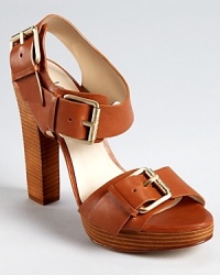 Bold buckles take center stage on KORS Michael Kors Chilali high heel sandals, luxe in tanned leather with a stacked sole. Bold buckles take center stage on KORS Michael Kors Chilali high heel sandals, luxe in tanned leather with a stacked sole.