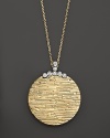 Diamonds add glamor to a beautifully textured 18K yellow gold disk on a 18K white gold chain. By Roberto Coin.