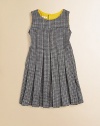 A retro, school-girl design in houndstooth goes modern with colorful piping at the neckline. Houndstooth patternRound neckline with contrast pipingSleevelessPleated bodice and skirtFit and flare silhouetteBack button closure50% fleece wool/50% viscoseMachine washMade in Italy