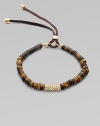 Beautifully textured tiger's eye-inspired beads accented with a center, rhinestone encrusted bead and an adjustable leather closure. Epoxy beadsGlass stonesGoldtone brassLeather cordDiameter, about 2½ stretchableLeather slide adjusterImported 