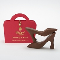 A pair of mini milk chocolate heels in a gold-stamped red box. A pair of mini milk chocolate heels in a gold-stamped red box.