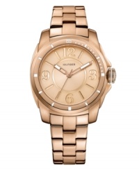 Classically styled timepiece with popping rosy hues, by Tommy Hilfiger. Crafted of rose-gold tone stainless steel bracelet and round case. Rose-gold tone dial features Arabic numerals at three, six, nine and twelve o'clock, stick indices, three hands and logo at twelve o'clock. Quartz movement. Water resistant to 30 meters. Ten-year limited warranty. Classically styled timepiece with popping rosy hues, by Tommy Hilfiger. Crafted of rose-gold tone stainless steel bracelet and round case. Rose-gold tone dial features Arabic numerals at three, six, nine and twelve o'clock, stick indices, three hands and logo at twelve o'clock. Quartz movement. Water resistant to 30 meters. Ten-year limited warranty.