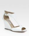 A minimalist t-strap style of glossy patent leather, uplifted by a comfortable wedge. Lacquered wedge, 3½ (90mm)Patent leather upperAdjustable ankle strapLeather lining and solePadded insoleMade in Italy