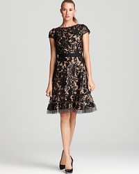 Tadashi Shoji's cap-sleeved creation showcases floral lace covered in sequins and sheer horsewire trim for fashion-forward flair. Tadashi Shoji's cap-sleeved creation showcases floral lace covered in sequins and sheer horsewire trim for fashion-forward flair.