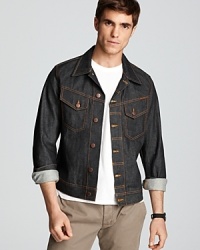 Dry denim jacket with two buttoned pockets at chest. Tabs at waist for a better fit. Squiggly stitching on back yoke. Contrast orange stitching throughout. Dry denim jacket with two buttoned pockets at chest. Tabs at waist for a better fit. Squiggly stitching on back yoke. Contrast orange stitching throughout.