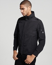 Zip front hooded jacket with covered snap buton placket, snaps at cuffs. Covered side slit hand pockets, zip pocket at arm. Armhole vents to prevent balooning. Roll in hoodie. Zip front hooded jacket with covered snap buton placket, snaps at cuffs. Covered side slit hand pockets, zip pocket at arm. Armhole vents to prevent balooning. Roll in hoodie.