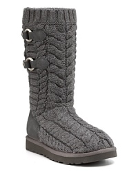 Snappy side buckles adorn these cozy cable knit boots--a stylish essential for cool days. By UGG® Australia. Snappy side buckles adorn these cozy cable knit boots--a stylish essential for cool days. By UGG® Australia.