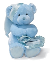 Key-wind musical bear gripping a blanket with a satin trim. Music plays Brahms Lullaby and the bear's head sways to music.