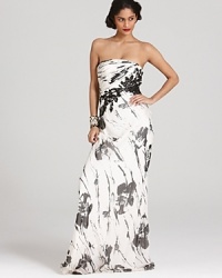 Sequin-adorned lace appliqués sparkle on this Carmen Marc Valvo strapless gown, emboldened by an abstract floral print. Sequin-adorned lace appliqués sparkle on this Carmen Marc Valvo strapless gown, emboldened by an abstract floral print.