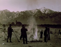 1943 Burning leaves, autumn dawn, Manzanar Relocation Center, California / photograph by Ansel Adams. SUMMARY: Group of men and boys standing around a small brush fire holding shovels, a pitchfork stands in the right foreground, mountains in background. V 1943 Burning leaves, autumn dawn, Manzanar Relocation Center, California / photograph by Ansel Adams. SUMMARY: Group of men and boys standing around a small brush fire holding shovels, a pitchfork stands in the right foreground, mountains in background. V