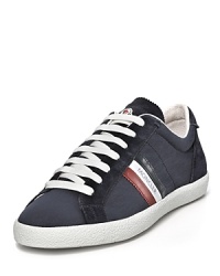 Moncler flies its signature triple stripe logo flag along the sides of this retro-informed lace up sneaker. Moncler flies its signature triple stripe logo flag along the sides of this retro-informed lace up sneaker.