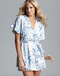 A short sleeve scroll/floral print wrap with ruffle trim and self tie at waist. A short sleeve scroll/floral print wrap with ruffle trim and self tie at waist.