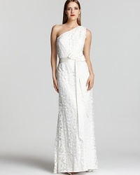 Delicate lace elegantly skims the body on this exquisite gown from Tadashi Shoji, complete with a waist-defining ribbon sash. Delicate lace elegantly skims the body on this exquisite gown from Tadashi Shoji, complete with a waist-defining ribbon sash.