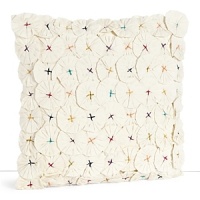 A detailed, textural decorative pillow covered in folded fabric flowers and anchored by multicolored embroidered dots.