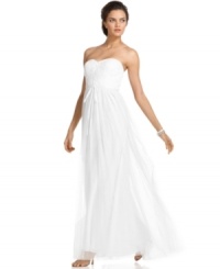 This beautiful gown by Adrianna Papell features a flower-inspired applique at the bust, a ribbon tie at the empire waist and a long, flowing skirt for a sweeping, sweet silhouette. This beautiful gown by Adrianna Papell features a flower-inspired applique at the bust, a ribbon tie at the empire waist and a long, flowing skirt for a sweeping, sweet silhouette.