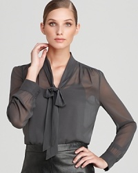 A sheer silhouette lends provocative edge to a classic DKNY blouse, flaunting a generous neck tie for an alluring feminine statement. A sheer silhouette lends provocative edge to a classic DKNY blouse, flaunting a generous neck tie for an alluring feminine statement.
